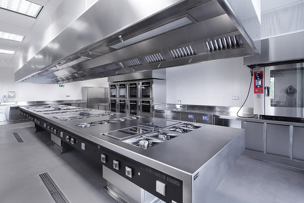 Instalación de sistema de extracción de humos con gran campana industrial de acero inoxidable en cocina de restaurante en Valencia